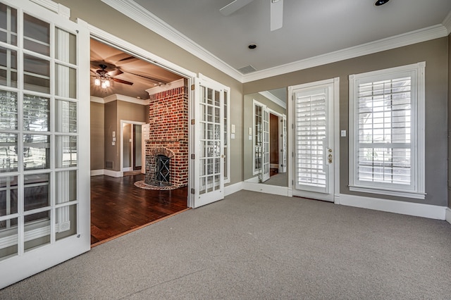 spare room featuring a fireplace, crown molding, wood-type flooring, and ceiling fan