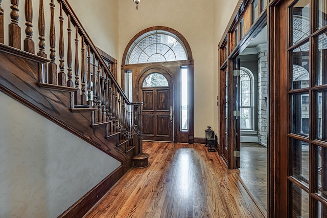 entrance foyer with hardwood / wood-style floors and a towering ceiling