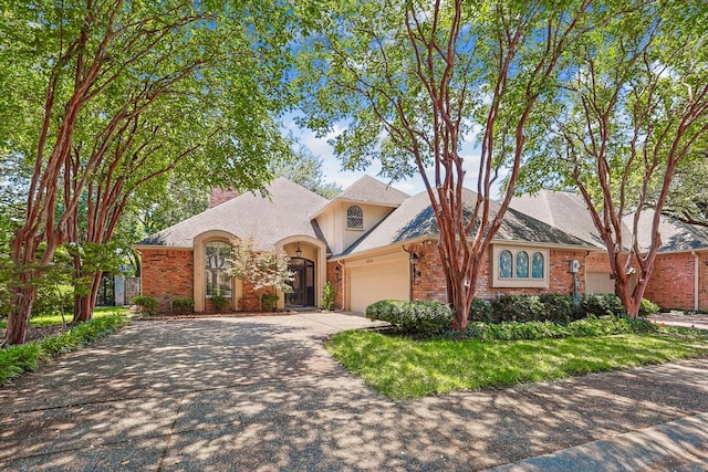 view of front of home with an attached garage, brick siding, and driveway