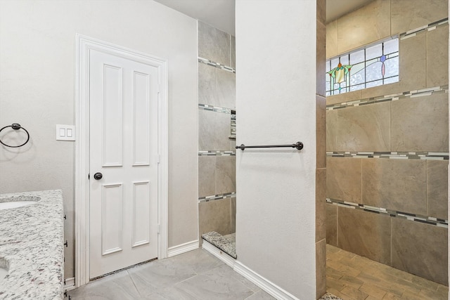 bathroom featuring tiled shower and vanity