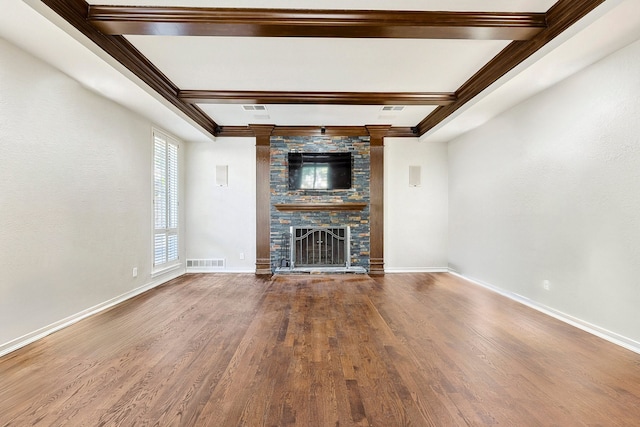 unfurnished living room featuring hardwood / wood-style flooring, beam ceiling, and a stone fireplace