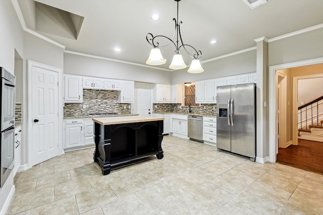 kitchen featuring a kitchen island, stainless steel appliances, white cabinetry, and tasteful backsplash