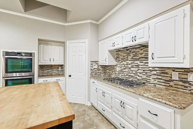 kitchen featuring ornamental molding, wood counters, decorative backsplash, appliances with stainless steel finishes, and white cabinets