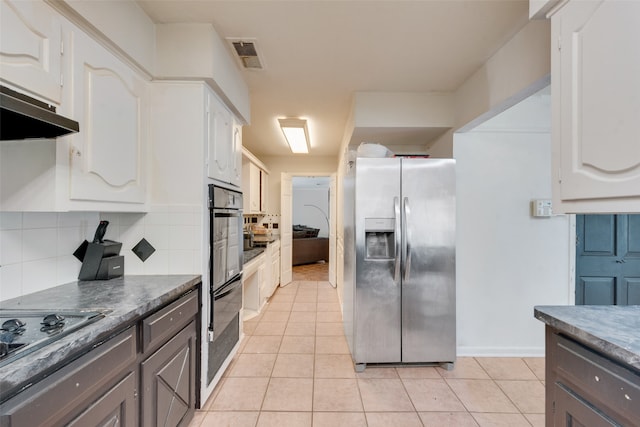 kitchen featuring light tile patterned floors, appliances with stainless steel finishes, white cabinetry, and decorative backsplash