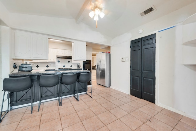 kitchen with stainless steel fridge, light tile patterned floors, a breakfast bar, ceiling fan, and white cabinets