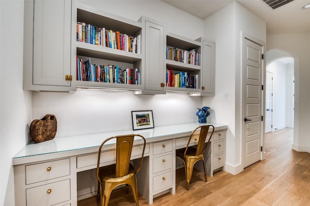 office space featuring built in desk and light hardwood / wood-style flooring