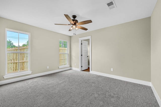 carpeted spare room featuring ceiling fan and plenty of natural light