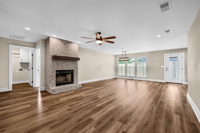 unfurnished living room featuring dark wood-type flooring, ceiling fan, and a stone fireplace