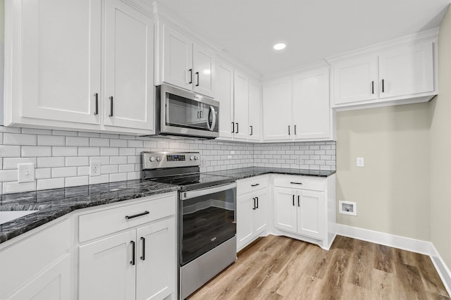 kitchen featuring light wood-type flooring, dark stone countertops, decorative backsplash, appliances with stainless steel finishes, and white cabinets