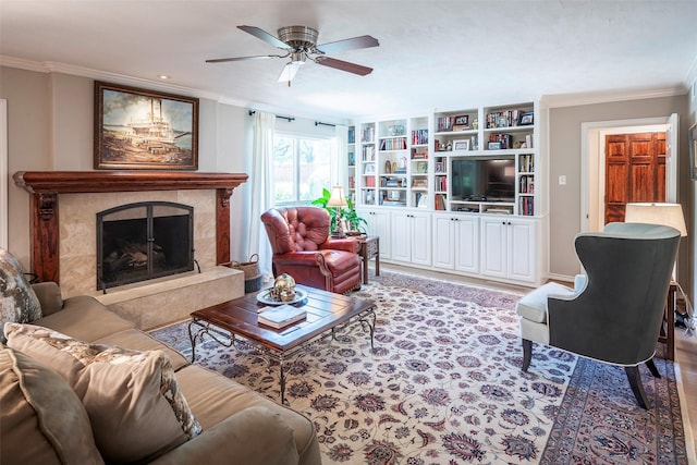 living room featuring built in features, a high end fireplace, ornamental molding, and ceiling fan