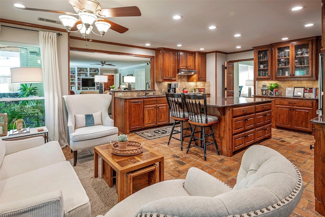 kitchen with tasteful backsplash, sink, a kitchen breakfast bar, kitchen peninsula, and crown molding