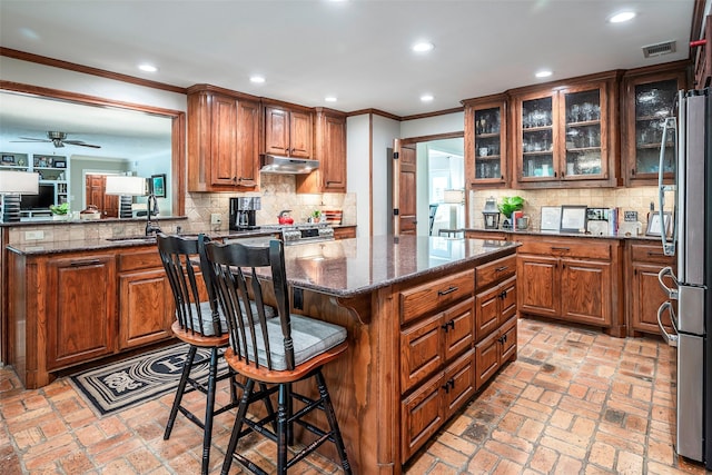 kitchen with backsplash, dark stone countertops, a breakfast bar, sink, and appliances with stainless steel finishes