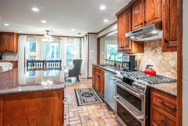 kitchen featuring stainless steel appliances, dark stone countertops, decorative backsplash, sink, and ornamental molding