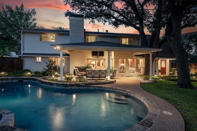 pool at dusk with outdoor lounge area and a patio