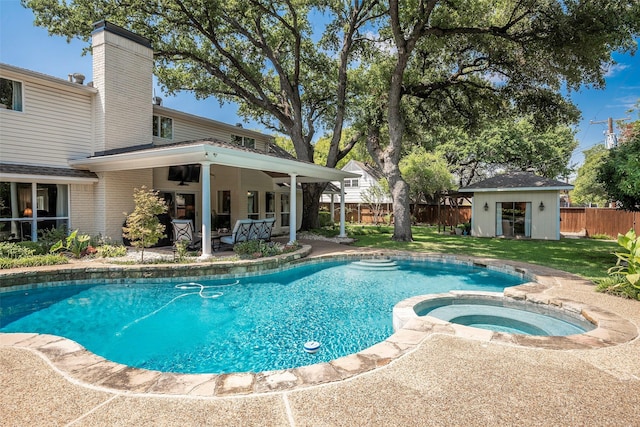 view of swimming pool with ceiling fan, a patio area, an outbuilding, and an in ground hot tub