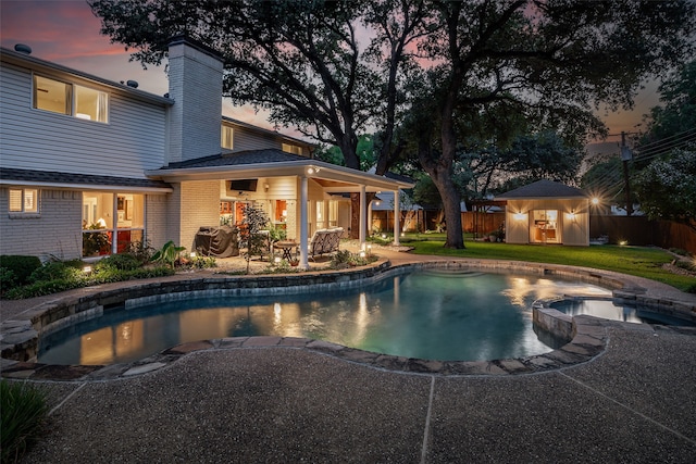 pool at dusk with a patio area, a lawn, and ceiling fan