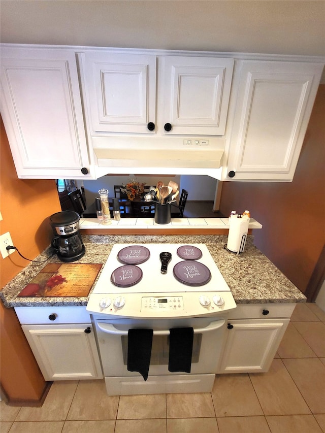 kitchen with light stone countertops, white cabinetry, light tile patterned floors, and white electric range oven