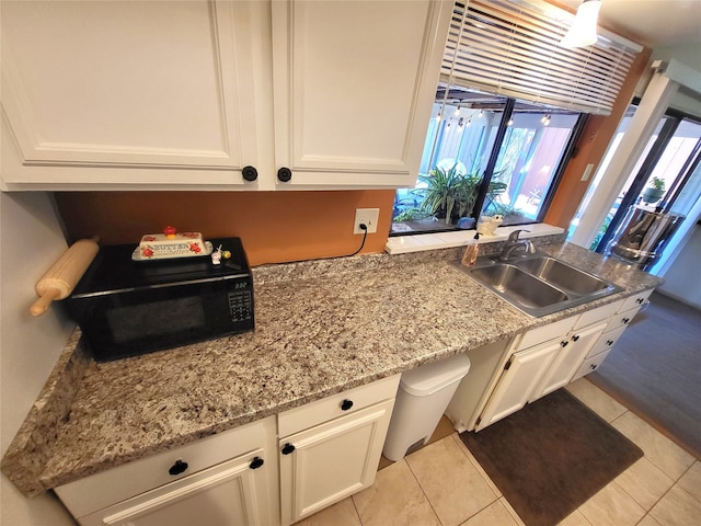 kitchen with light tile patterned floors, white cabinetry, and sink