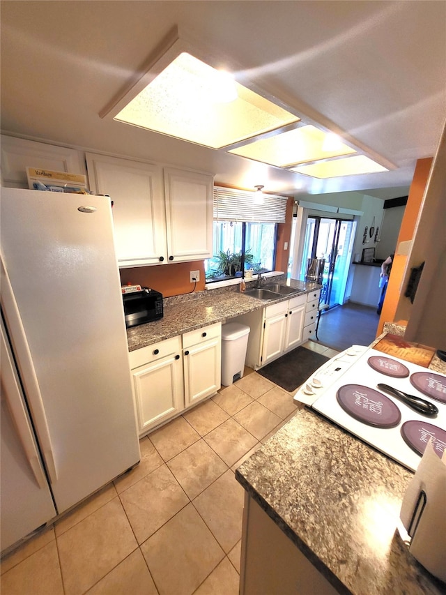 kitchen featuring white appliances, ceiling fan, sink, light tile patterned floors, and white cabinets