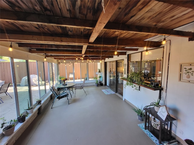 unfurnished sunroom featuring beamed ceiling and a healthy amount of sunlight