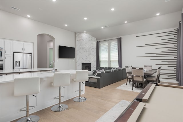 kitchen with light wood-type flooring, appliances with stainless steel finishes, white cabinetry, sink, and a breakfast bar area