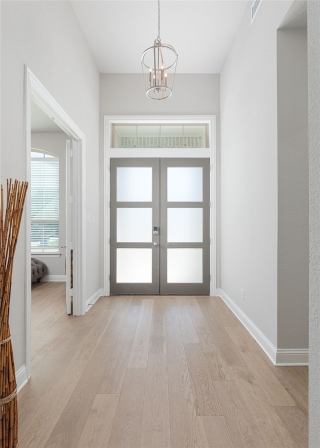 foyer featuring french doors, a notable chandelier, and light hardwood / wood-style flooring