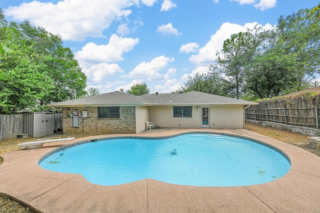 view of swimming pool featuring a diving board and a patio