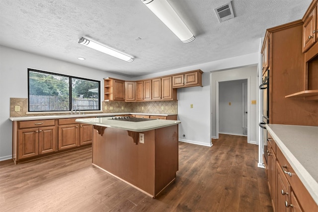 kitchen with black electric stovetop, a kitchen breakfast bar, a center island, decorative backsplash, and dark hardwood / wood-style floors