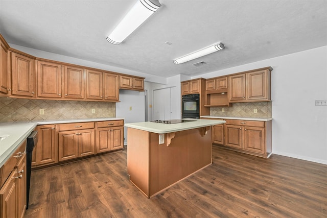 kitchen with tasteful backsplash, black appliances, a kitchen island, a breakfast bar, and dark hardwood / wood-style floors