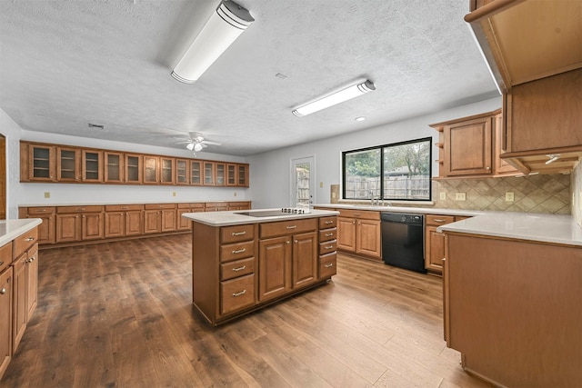 kitchen featuring black appliances, a center island, decorative backsplash, hardwood / wood-style flooring, and ceiling fan