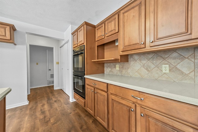 kitchen featuring a textured ceiling, dark hardwood / wood-style flooring, backsplash, and double oven