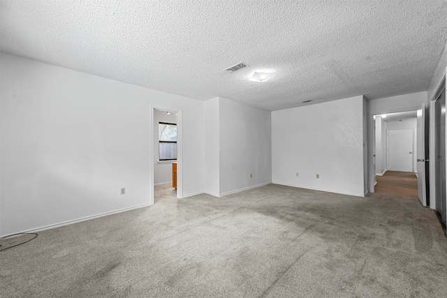 empty room featuring a textured ceiling and light colored carpet