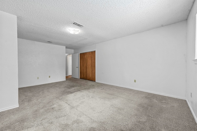 unfurnished room with a textured ceiling and light colored carpet