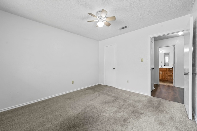 empty room featuring ceiling fan, a textured ceiling, and dark colored carpet