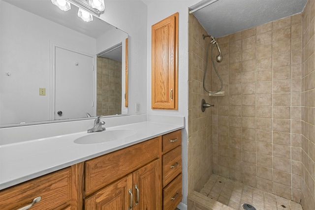 bathroom with a tile shower, a textured ceiling, and vanity