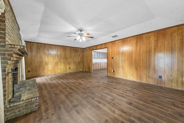 unfurnished living room featuring dark wood-type flooring, ceiling fan, a fireplace, and a textured ceiling