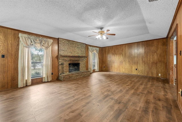 unfurnished living room featuring a textured ceiling, a brick fireplace, wood-type flooring, and ceiling fan