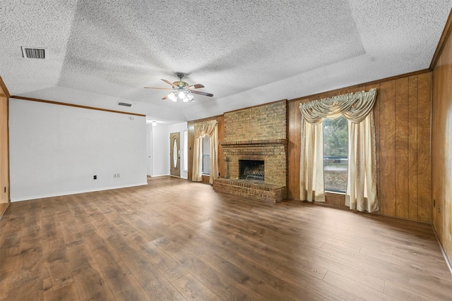 unfurnished living room featuring a textured ceiling, ceiling fan, wood walls, and a fireplace