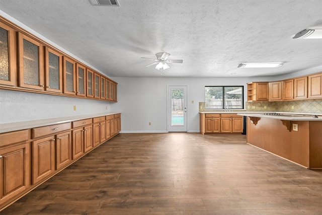 kitchen featuring tasteful backsplash, a textured ceiling, a kitchen bar, ceiling fan, and hardwood / wood-style flooring