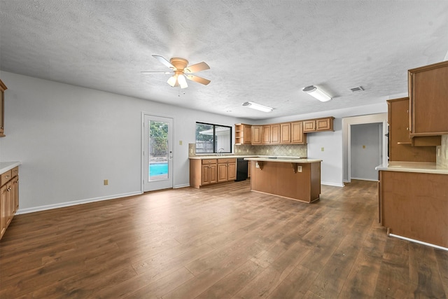 kitchen with dark hardwood / wood-style flooring, dishwasher, backsplash, a breakfast bar, and ceiling fan