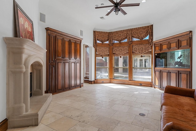 living room with a ceiling fan, visible vents, and a high ceiling