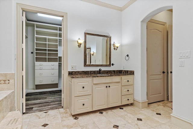 full bathroom featuring tile patterned flooring, a walk in closet, vanity, and crown molding