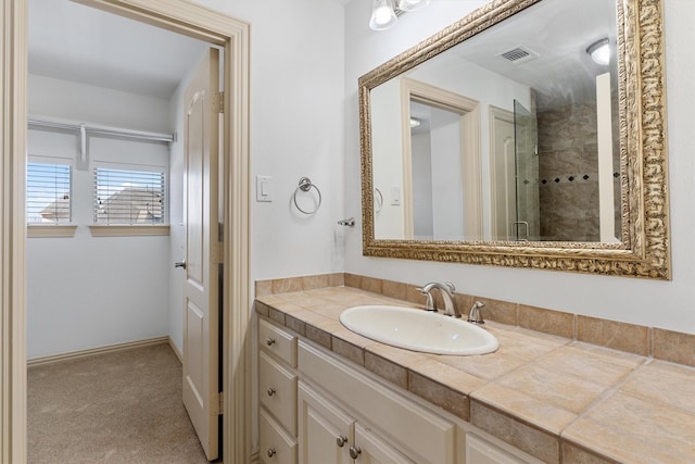 bathroom with visible vents, vanity, and tiled shower