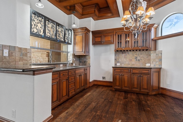 kitchen with baseboards, dark wood finished floors, glass insert cabinets, brown cabinets, and a sink