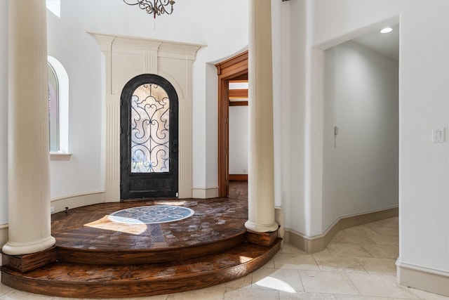 foyer entrance with baseboards, arched walkways, and ornate columns