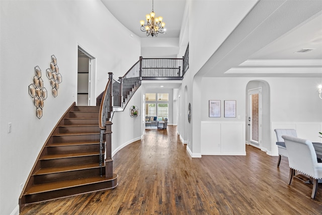 entryway featuring dark wood-type flooring, a notable chandelier, a towering ceiling, and a tray ceiling