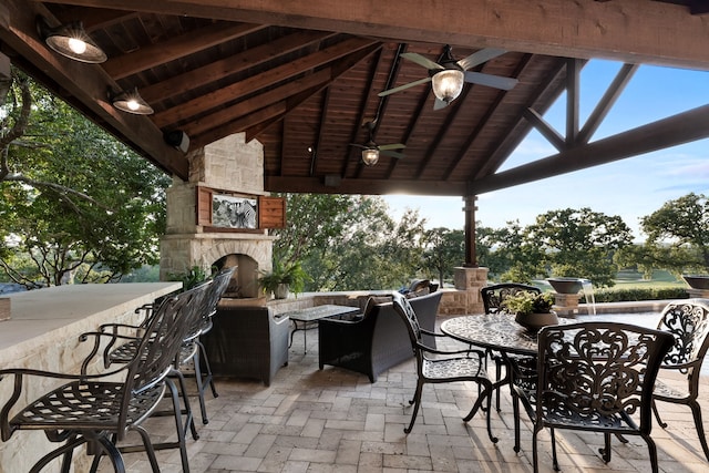 view of patio / terrace with an outdoor stone fireplace, an outdoor bar, ceiling fan, and a gazebo