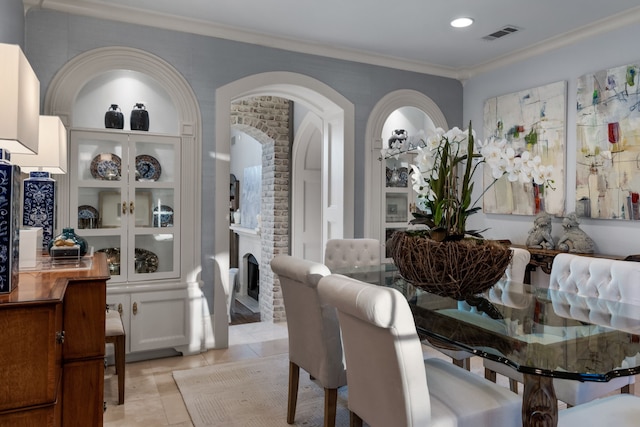 tiled dining room with a fireplace and crown molding