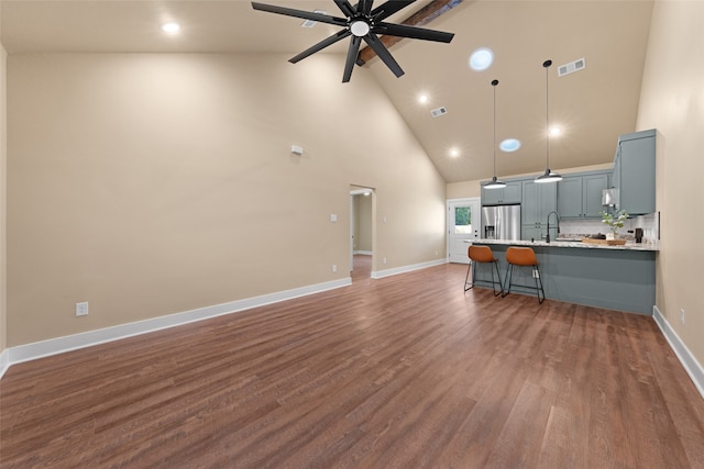 unfurnished living room with hardwood / wood-style flooring, high vaulted ceiling, sink, and ceiling fan