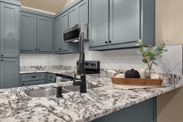 kitchen featuring light stone counters, stainless steel appliances, and decorative backsplash